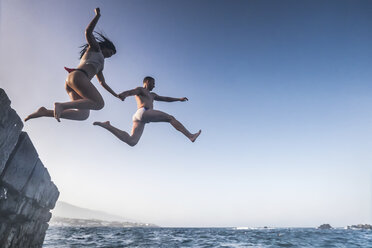 Spain, Tenerife, Young couple jumping from rock - SIPF000122