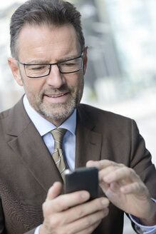 Porträt eines Geschäftsmannes mit Brille und Smartphone - GUFF000255