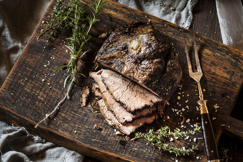 In Scheiben geschnittenes Roastbeef, Rosmarin, Thymian und Meersalz auf dem Schneidebrett - SBDF002649