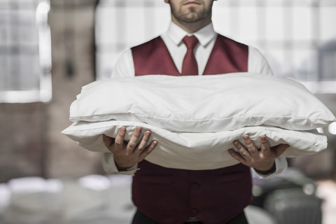 Butler im Hotelzimmer, der Kissen hält, lizenzfreies Stockfoto