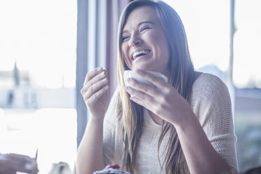 Porträt eines lachenden Teenagers mit einer Tasse Kaffee in einem Café - ZEF008068