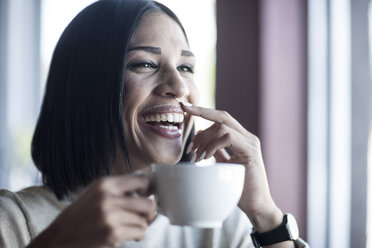 Porträt einer lachenden Frau mit Milchschnurrbart, die eine Tasse Kaffee hält - ZEF008071