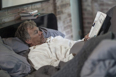 Mann liest eine Zeitschrift im Bett - ZEF008090