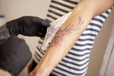 Hands of tattooist removing stencil - MFRF000485