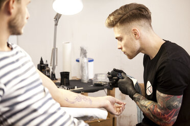 Tätowierer bei der Arbeit in seinem Tattoo-Studio - MFRF000487