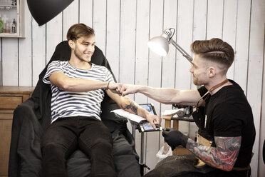 Tattooist and client giving fist bump after work is done - MFRF000498