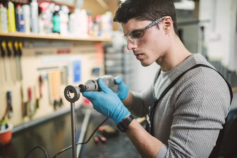 Junger Mechaniker bei der Arbeit in einer Reparaturwerkstatt, lizenzfreies Stockfoto