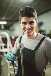 Junger Mechaniker bei der Arbeit in einer Reparaturwerkstatt - RAEF000793