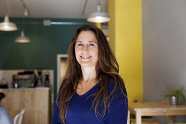 Portrait of a smiling woman standing in a restaurant - VABF000084