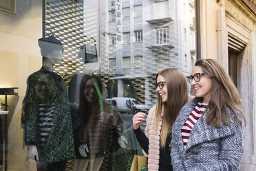 Italy, Belluno, two young women looking at window display of a fashion shop - ALBF000020