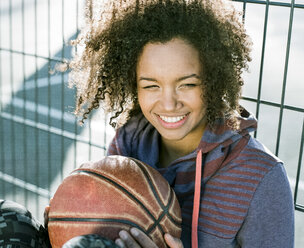Portrait of smiling young woman with basketball - MADF000776
