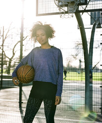 Porträt einer jungen Frau mit Basketball im Gegenlicht - MADF000779