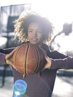 Porträt einer jungen Frau beim Basketballspielen im Gegenlicht - MADF000783