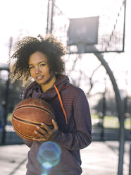 Portrait of young woman with basketball at backlight - MADF000784