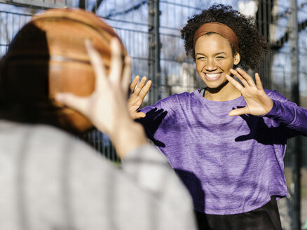 Porträt einer lächelnden jungen Frau beim Basketballspielen - MADF000787