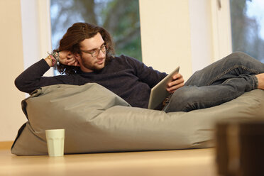 Junger Mann mit digitalem Tablet entspannt auf Sitzsack - LBF001359