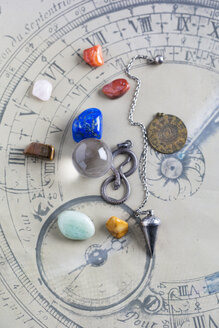 Semiprecious stones, pendulum, pendant and crystal ball on horoscope circle - MYF001325