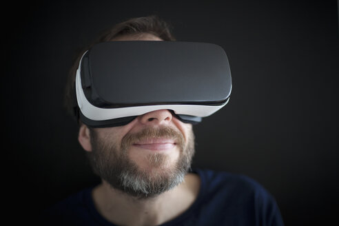 Lächelnder Mann mit Virtual-Reality-Brille - RBF004085
