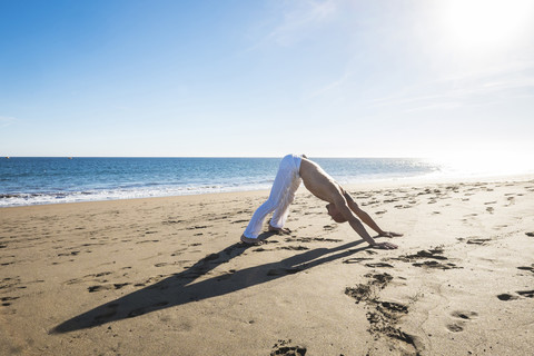 Spanien, Teneriffa, Mann macht Yoga-Übungen am Strand, lizenzfreies Stockfoto