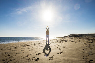 Spanien, Teneriffa, Mann macht Yoga-Übungen am Strand bei Gegenlicht - SIPF000144