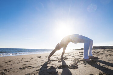 Spanien, Teneriffa, Mann macht Yoga-Übungen am Strand bei Gegenlicht - SIPF000145