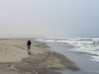 Namibia, Namib desert, woman on beach, freezing cold and stormy - AMF004709