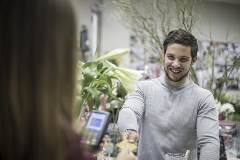 Lächelnder Kunde beim Bezahlen im Blumenladen - ZEF008117