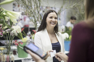 Lächelnder Kunde beim Bezahlen im Blumenladen - ZEF008118