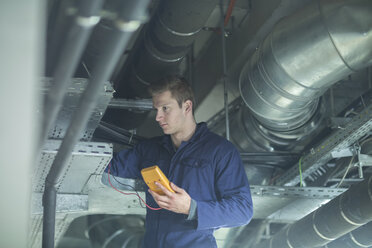 Young man in technical room checking pipe - SGF002010