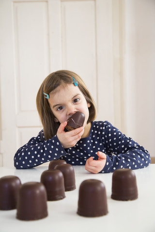 Porträt eines kleinen Mädchens, das einen Marshmallow aus Schokolade isst, lizenzfreies Stockfoto