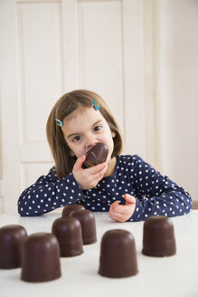 Porträt eines kleinen Mädchens, das einen Marshmallow aus Schokolade isst - LVF004486