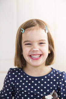 Porträt eines lachenden kleinen Mädchens, das einen Marshmallow aus Schokolade isst - LVF004487