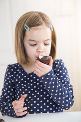 Porträt eines kleinen Mädchens, das einen Marshmallow aus Schokolade isst - LVF004489