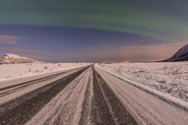 Norwegen, Lofoten Inseln, Nordlicht über einer Straße im Winter - LOMF000194