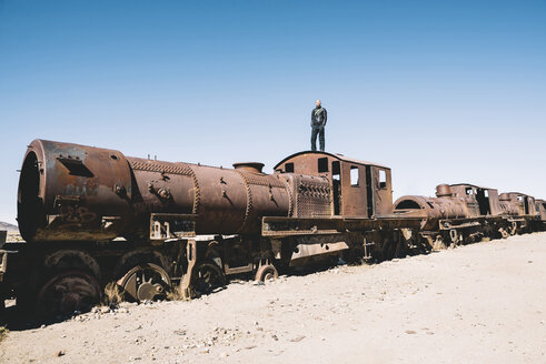 Bolivien, Zugfriedhof Uyuni, Mann steht auf dem Führerstand eines alten rostigen Zuges - GEMF000664