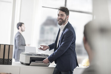 Smiling man in office using printer - ZEF008179