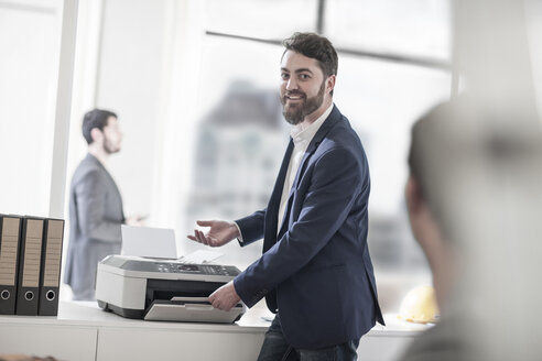 Lächelnder Mann im Büro mit Drucker - ZEF008179