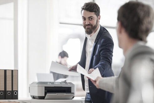 Lächelnder Mann im Büro, der einem Kollegen ein Blatt überreicht - ZEF008180