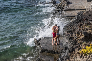 Spanien, Teneriffa, junges verliebtes Paar küsst sich auf einem Felsvorsprung - SIPF000148