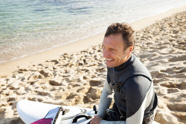 Lächelnder Mann am Strand mit Surfbrett - VABF000100