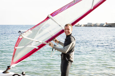 Lächelnder Mann beim Windsurfen auf dem Meer - VABF000103