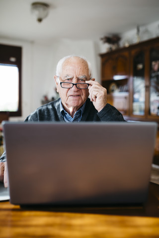 Porträt eines älteren Mannes mit Laptop zu Hause, lizenzfreies Stockfoto