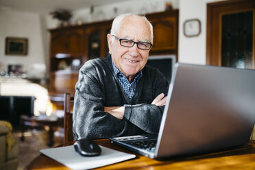 Porträt eines lächelnden älteren Mannes mit Laptop zu Hause - JRFF000363