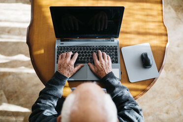 Senior man using laptop at home, top view - JRFF000365