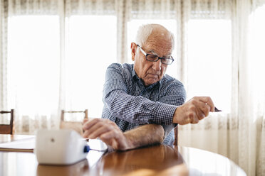 Älterer Mann kontrolliert seinen Blutdruck zu Hause - JRFF000369