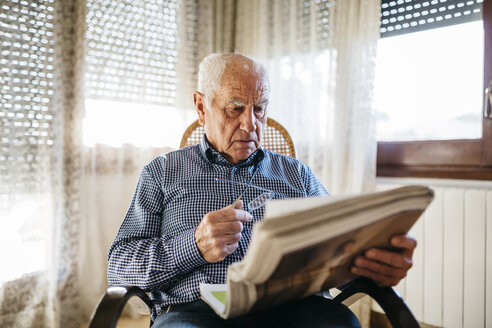 Senior man reading newspaper at home - JRFF000373
