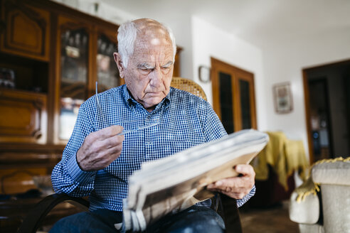 Senior man reading newspaper at home - JRFF000374