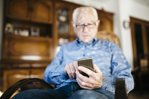 Älterer Mann benutzt Smartphone zu Hause, Nahaufnahme, lizenzfreies Stockfoto