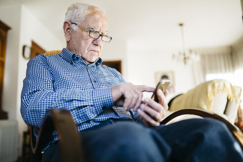 Älterer Mann benutzt Smartphone zu Hause - JRFF000380