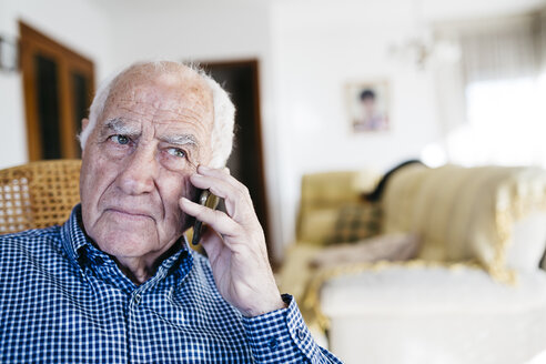 Porträt eines älteren Mannes, der zu Hause mit seinem Smartphone telefoniert - JRFF000382